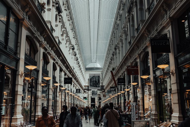A bustling indoor shopping arcade featuring a stunning skylight and classic architecture.