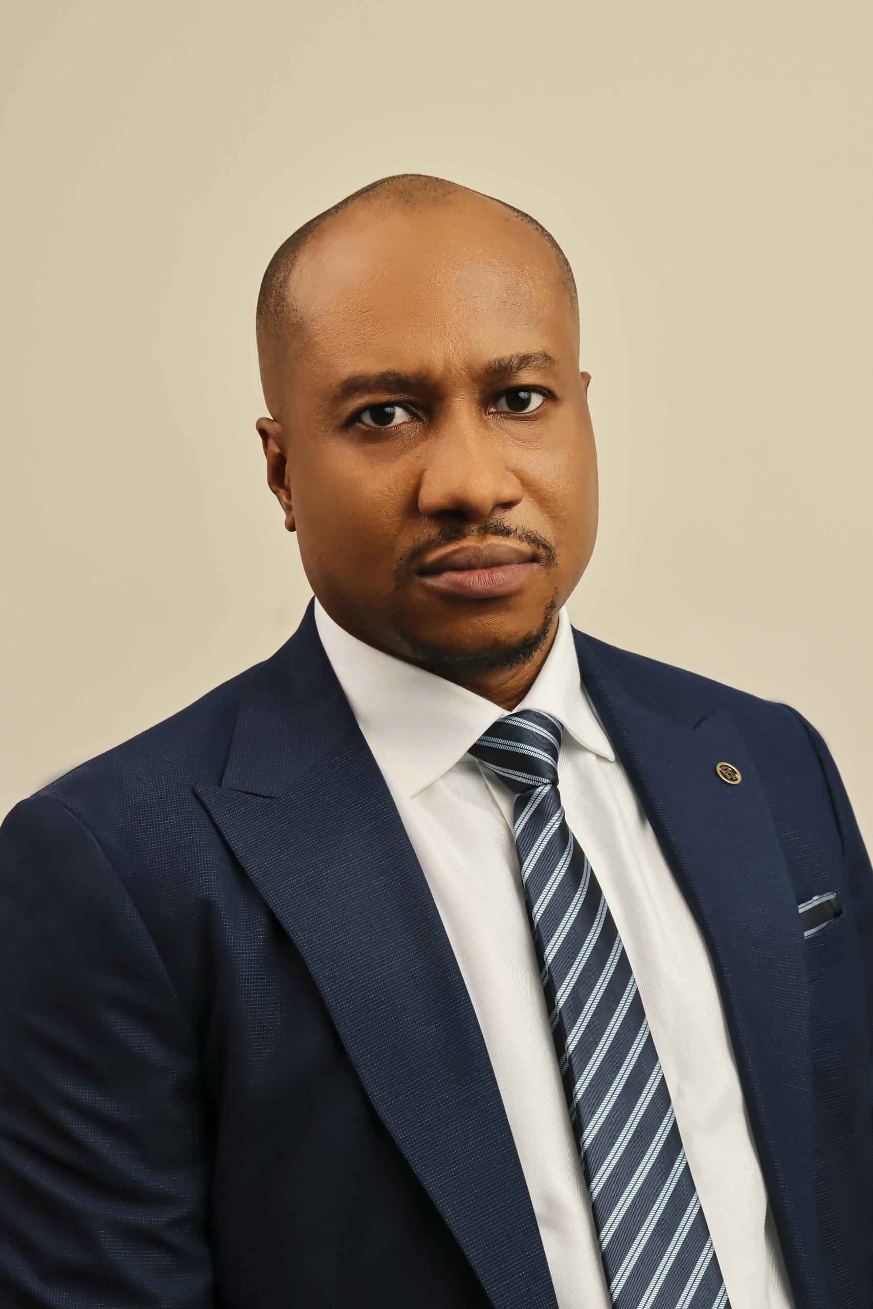 A professional portrait showcasing a bald, elegant businessman in a suit against a neutral background.
