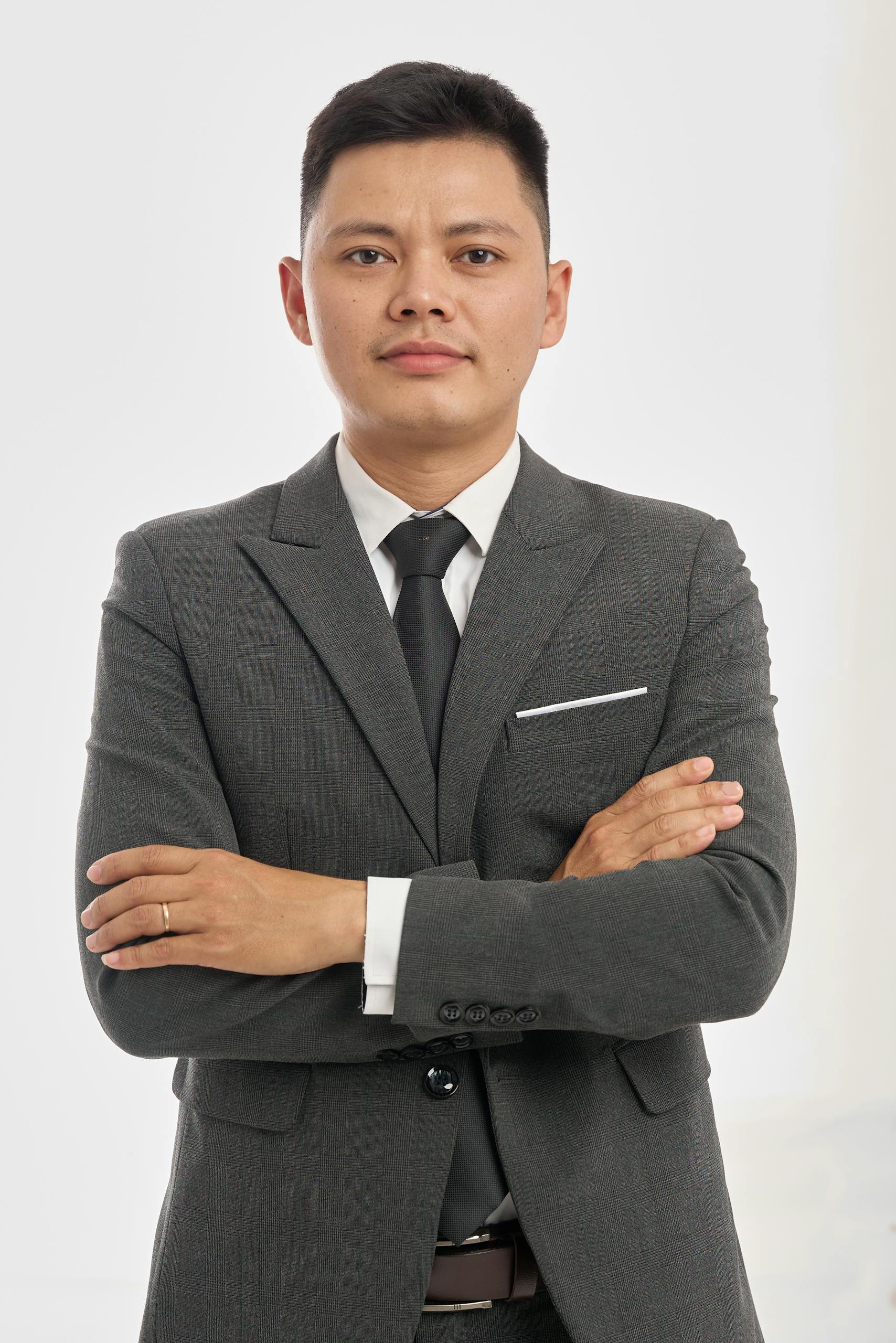 Portrait of a confident businessman in a formal suit with arms crossed, isolated on white background.