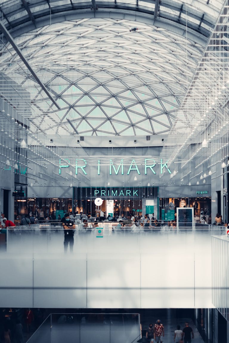 Spacious shopping mall interior featuring glass walls and Primark storefront.