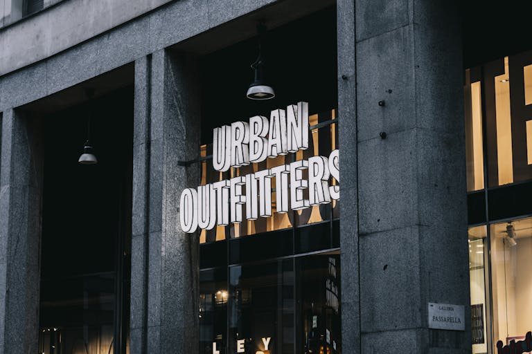 Urban Outfitters store entrance with illuminated signage in a city environment.